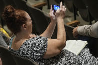 Jami Wallace takes a photo of a video display during a meeting of the National Transportation Safety Board to discuss and the Norfolk Southern Train Derailment Investigation Tuesday, June 25, 2024, in East Palestine, Ohio. (AP Photo/Sue Ogrocki)