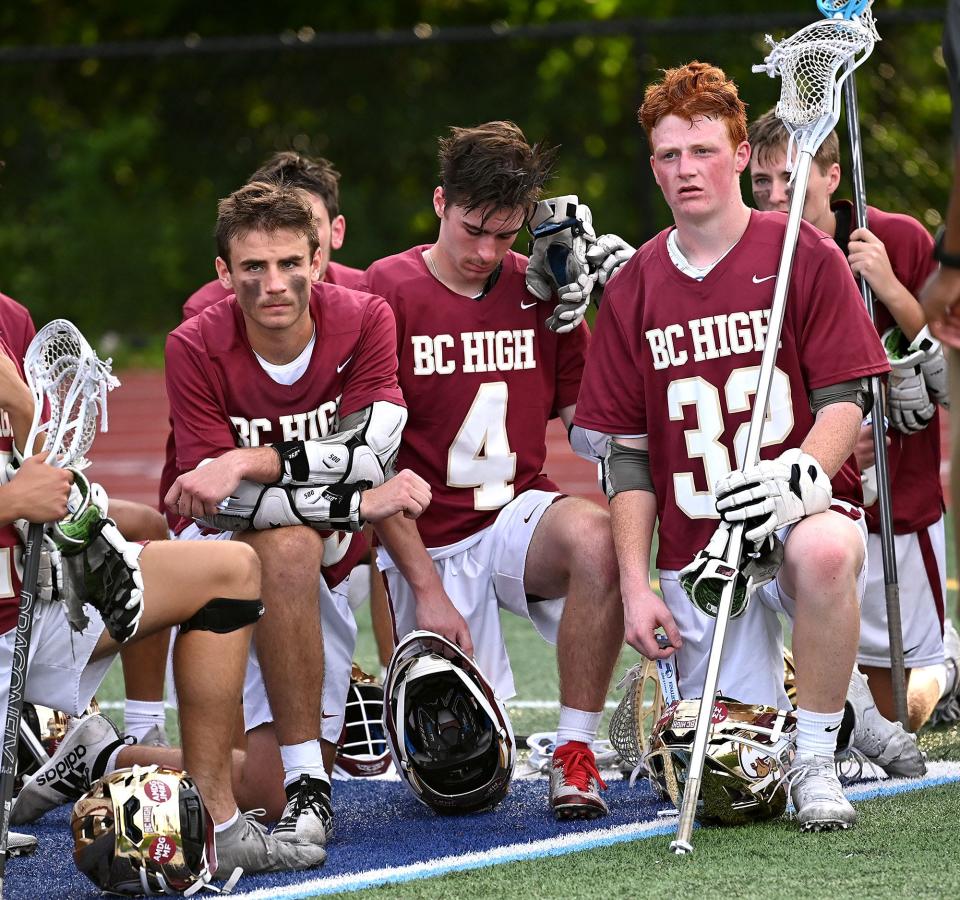 BC High players Will Emsing, left, Ronan Bailey and Jack Pyne listen to coaches after the 11-4 loss to St. John's Prep in the MIAA Division 1 boys lacrosse state championship at Worcester State University, June 21, 2022.