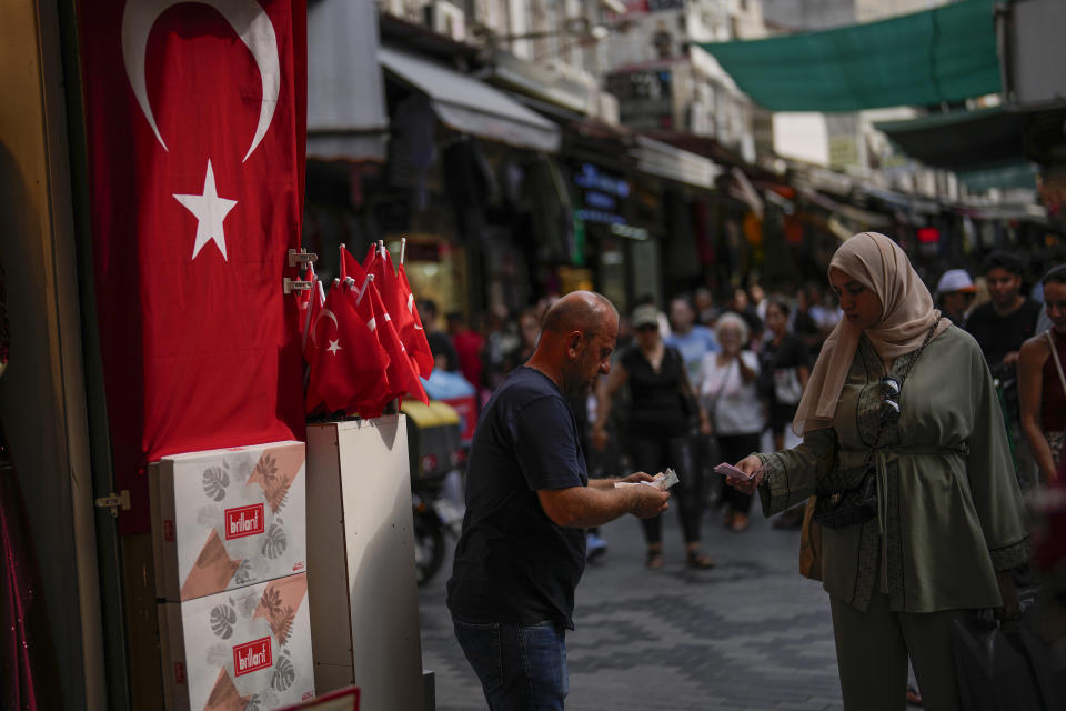 FILE - A seller talks to a customer in a street market in Istanbul, Turkey, on Sept. 6, 2023. Turkey’s central bank raised its key interest rate by 5 percentage points Thursday, another large but expected hike that signals a continued push toward more traditional economic policies under President Recep Tayyip Erdogan. (AP Photo/Francisco Seco, File)