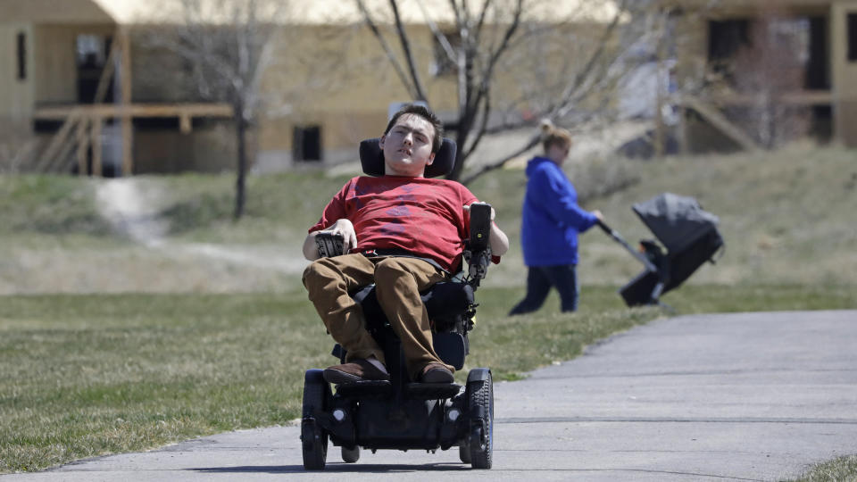 In this April 14, 2020, photo, Jacob Hansen rides near his house, in Eagle Mountain, Utah. Even before the new coronavirus hit, cystic fibrosis meant a cold could put Hansen in the hospital for weeks. He relies on hand sanitizer and disinfecting wipes to keep germs at bay because has cerebral palsy and uses a wheelchair, but these days shelves are often bare. For millions of disabled people and their families, the coronavirus crisis has piled on new difficulties and ramped up those that already existed. (AP Photo/Rick Bowmer)