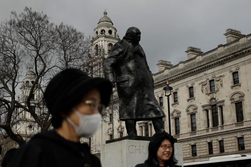 A tourist passes the statue of former British Prime Minister Winston Churchill in Parliament Square in London, where Prime Minister Boris Johnson recently announced he has tested positive for COVID-19.