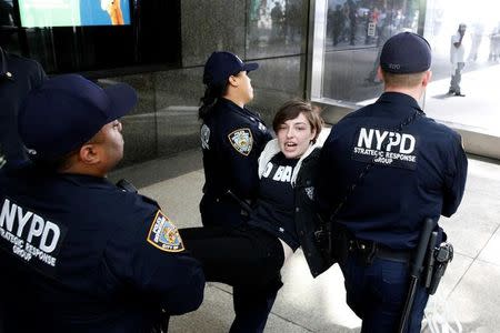 New York City Police officers (NYPD) carry a protestor after making arrests for demonstrating in Trump Tower in New York City, U.S., April 13, 2017. REUTERS/Brendan McDermid