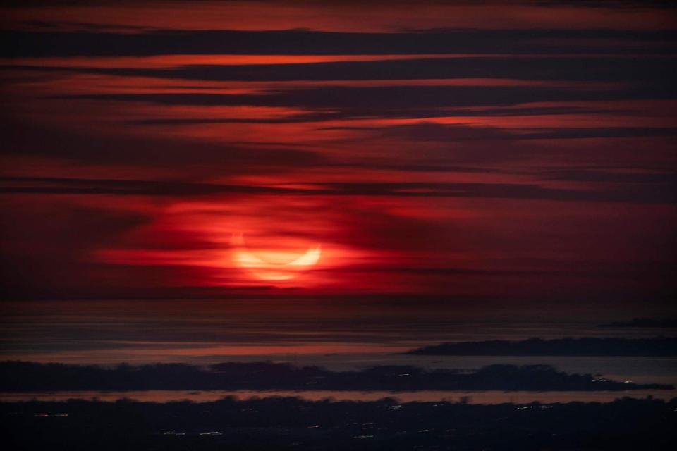 The sun rises partially eclipsed in this view taken from behind a window (hence the doubling effect) of  Summit One Vanderbilt, a high rise in New York City (AFP via Getty Images)