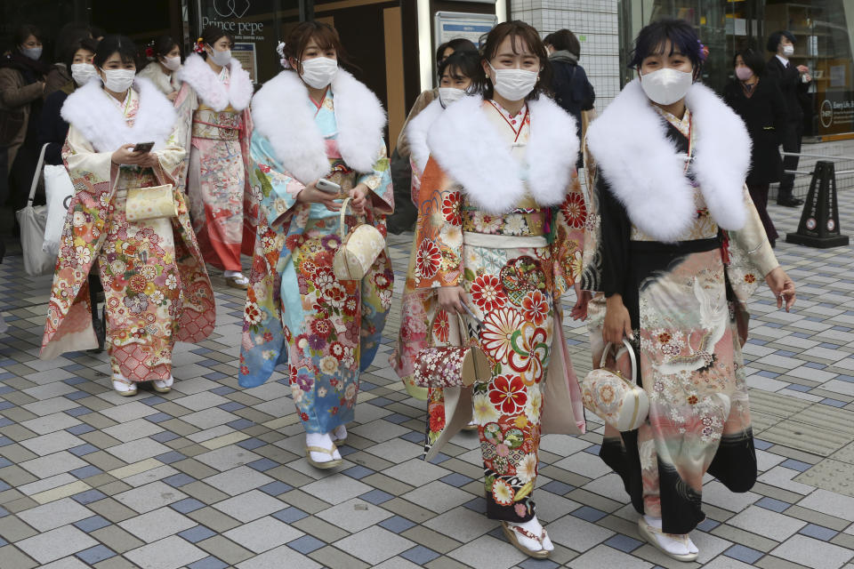 Kimono-clad women wearing face masks to protect against the spread of the coronavirus walk out after a Coming-of-Age ceremony in Yokohama, near Tokyo, Monday, Jan. 11, 2021. The Tokyo area has been under a state of emergency since Friday to try to stop the spread of the virus. (AP Photo/Koji Sasahara)