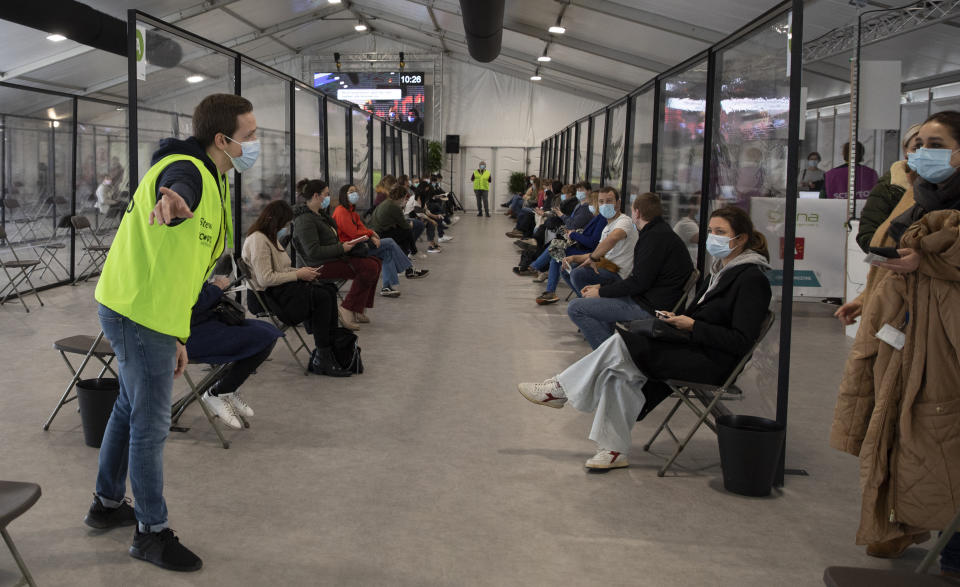 A steward directs people to seats in a waiting room after receiving an injection of the AstraZeneca coronavirus vaccine at the Vaccine Village in Antwerp, Belgium, on Friday, Feb. 19, 2021. (AP Photo/Virginia Mayo)