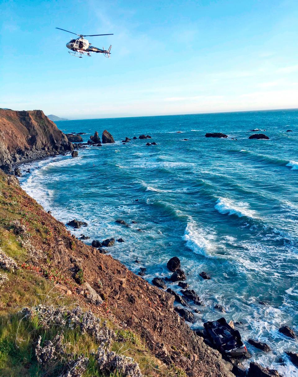 In this March 27, 2018, file photo provided by the California Highway Patrol a helicopter hovers over steep coastal cliffs near Mendocino, Calif., where a vehicle, visible at lower right, plunged about 100 feet off a cliff along Highway 1, killing all passengers.