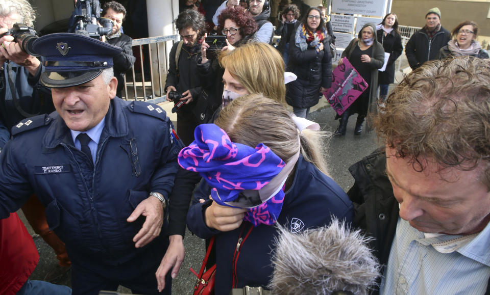 A 19-year old British woman, center, covers her face as she leaves from the Famagusta court after her trial, in Paralimni, Cyprus, Monday, Dec. 30, 2019. A Cyprus court on Monday found a 19 year-old British woman guilty of fabricating claims that she was gang raped by 12 Israeli men. (AP Photo/Philippos Christou)