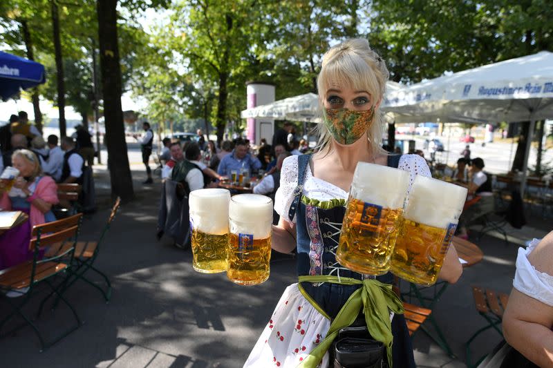Server carries mugs during the tapping of a barrel at a beer garden near Theresienwiese