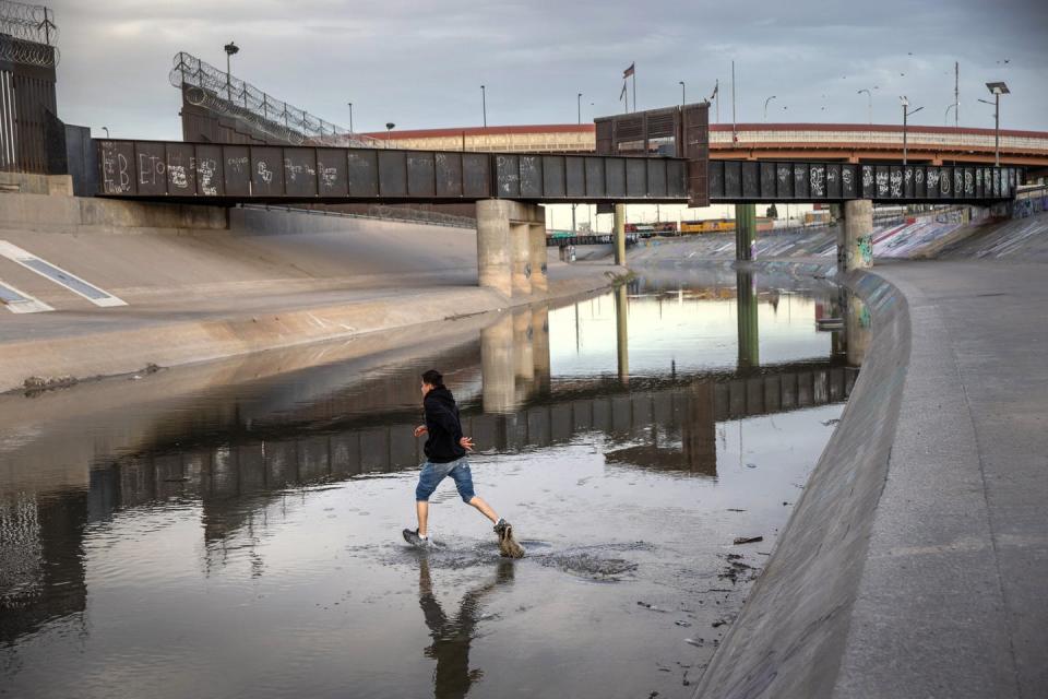 Boy runs across a shallow, water-filled gully