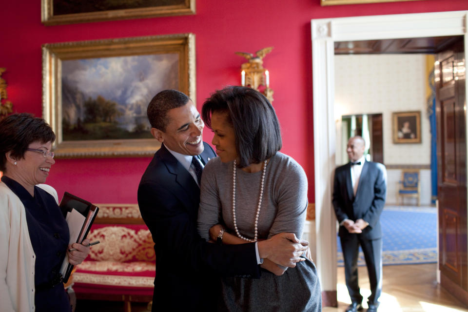 President Barack Obama hugs first lady Michelle Obama in the Red Room while Senior Advisor Valerie Jarrett (L) smiles prior to the National Newspaper Publishers Association (NNPA) at the White House on March 20, 2009, in Washington, D.C.