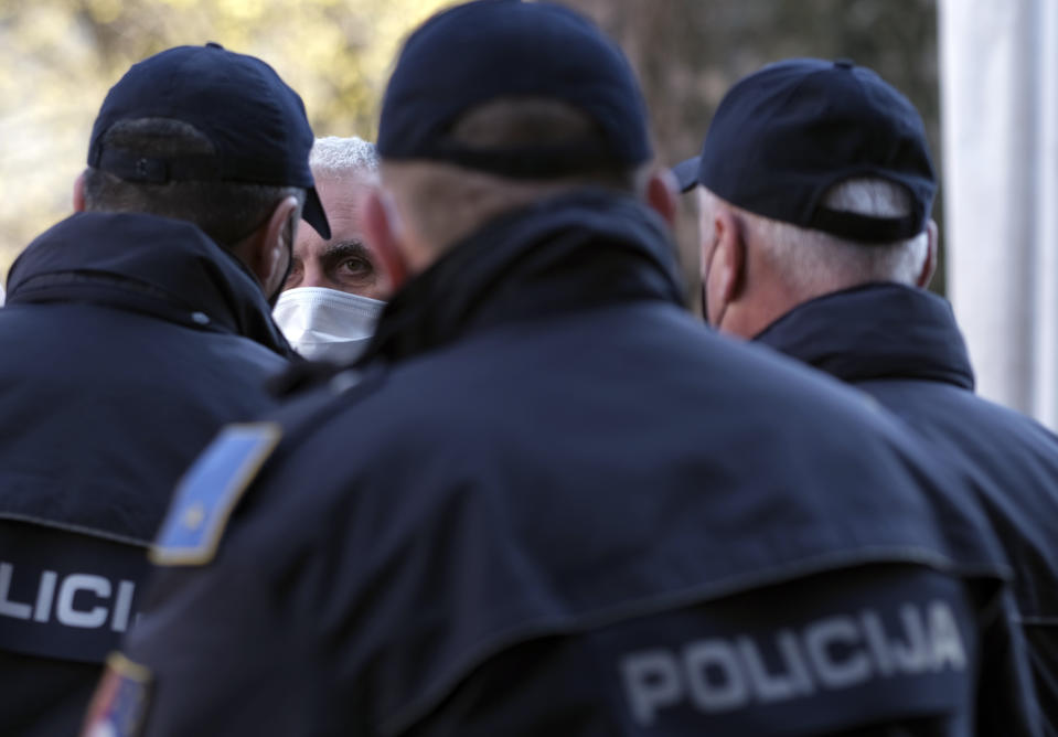 A man wearing a face mask to protect against coronavirus argues with police officers during protest against anti-virus measures in the capital Sarajevo, Bosnia, Thursday, March 11, 2021. Several hundred owners of small businesses have briefly blocked traffic in Bosnia's capital Sarajevo in protest of anti-virus measures for the upcoming weekend. Bosnian authorities have announced that all non-essential shops and businesses, including bars and restaurants in Sarajevo will shut down on Friday as the country faces a surge in coronavirus infections. (AP Photo/Kemal Softic)