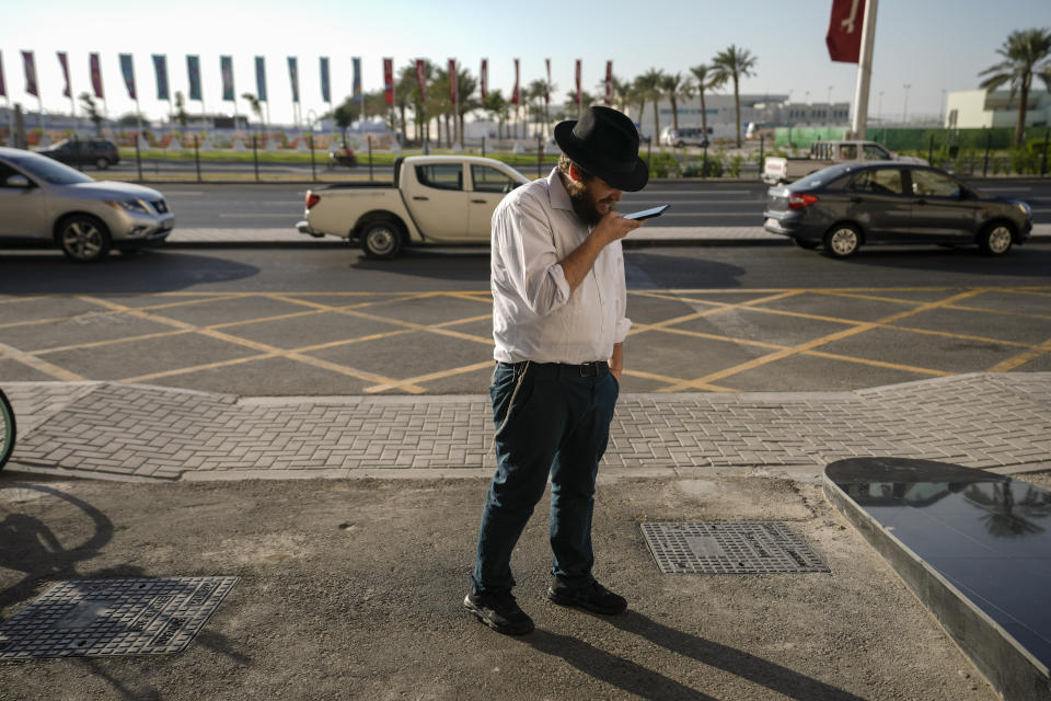 Eli Chitrik from Turkey records a voice note on his phone outside hotel in Doha, Qatar, Monday, Nov. 28, 2022. Stored into bright orange cases in Rabbi Eli Chitrik’s hotel room are bagels stuffed with vegetables. The labels declare the sandwiches kosher, or in compliance with Judaism’s set of dietary regulations. Freshly baked, they are made in Qatar at a designated kitchen, set up to feed Jewish World Cup visitors who want to keep kosher during the tournament. (AP Photo/Moises Castillo)