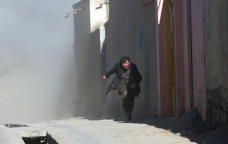 <p>An Afghan man runs away as dust blows in the aftermath of the third blast at a Shiite cultural centre in Kabul on Dec. 28, 2017. (Photo: Shah Marai/AFP/Getty Images) </p>