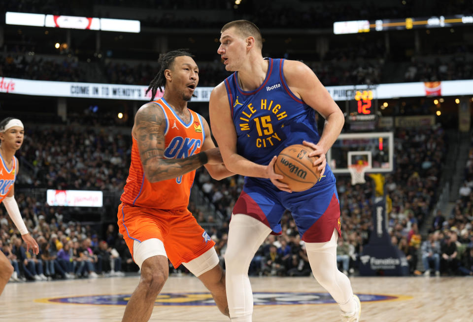 Denver Nuggets center Nikola Jokic (15) turns toward the basket as Oklahoma City Thunder forward Jaylin Williams, center left, defends in the first half of an NBA basketball game Saturday, Dec. 16, 2023, in Denver. (AP Photo/David Zalubowski)