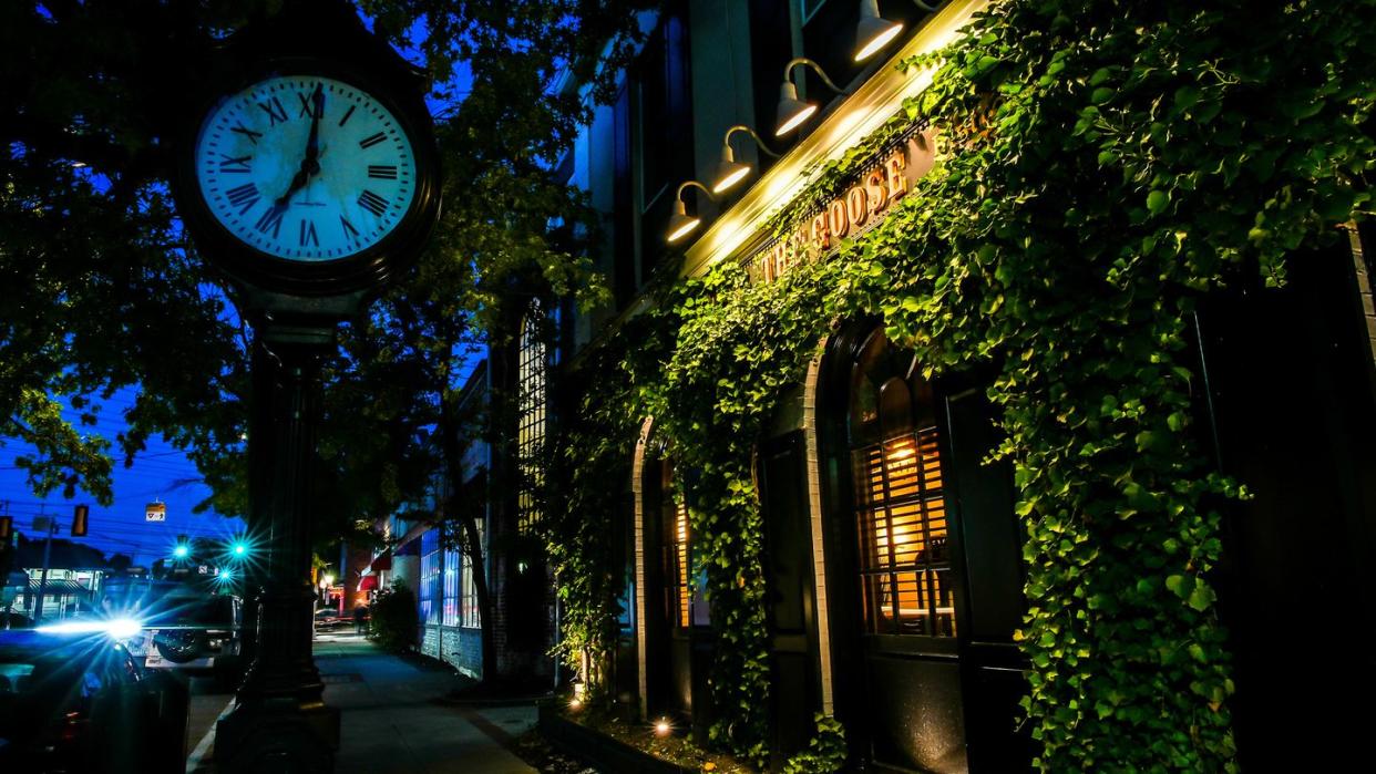 the goose bistro facade with sign and clock near post road with evening lights