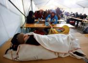 A child rests as other migrants wait inside a tent at the the Berlin Office of Health and Social Affairs (LAGESO), in Berlin, Germany, January 5, 2016. REUTERS/Hannibal Hanschke