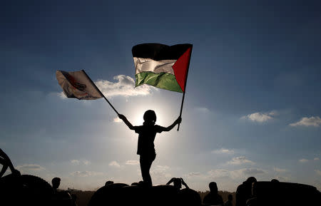 A boy waves a Palestinian flag during a protest calling for lifting the Israeli blockade on Gaza and demanding the right to return to their homeland, at the Israel-Gaza border fence, east of Gaza City September 14, 2018. REUTERS/Mohammed Salem