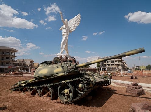 <span class="caption">An Islamic State tank beneath a statue of a Kurdish fighter in Kobanî, northern Syria</span> <span class="attribution"><span class="source">Elise Marie Boyle Espinosa</span>, <span class="license">Author provided</span></span>