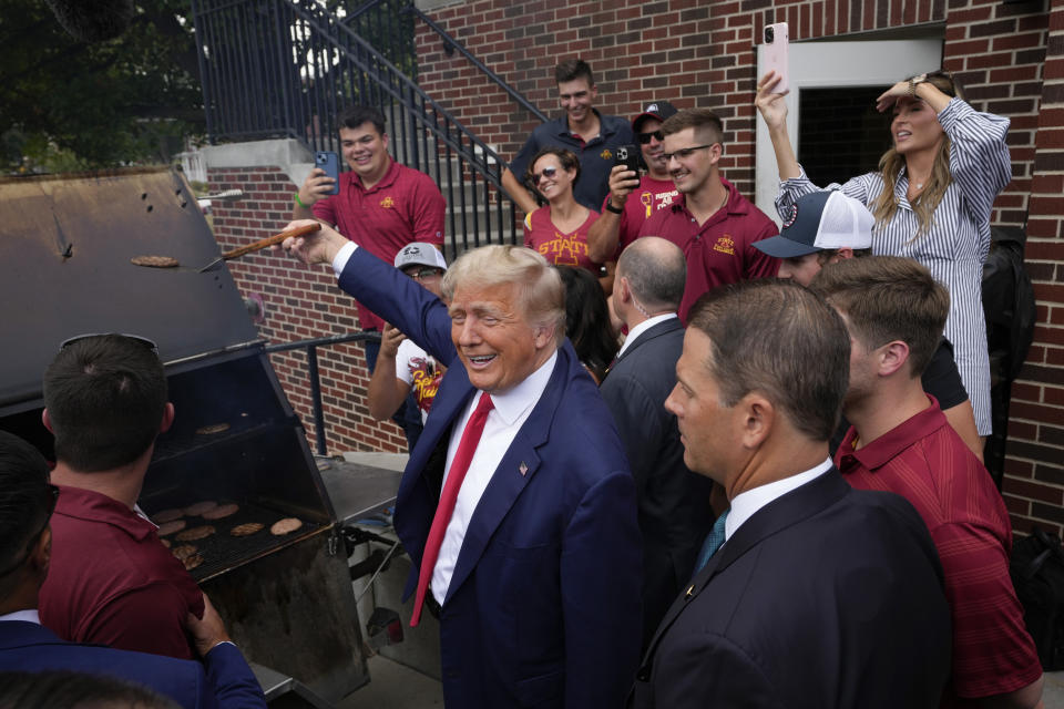 Former President Donald Trump holds a spatula with a hamburger on it as he works the grill during a stop at the Alpha Gamma Rho, agricultural fraternity, at Iowa State University before an NCAA college football game between Iowa State and Iowa, Saturday, Sept. 9, 2023, in Ames, Iowa. (AP Photo/Charlie Neibergall)