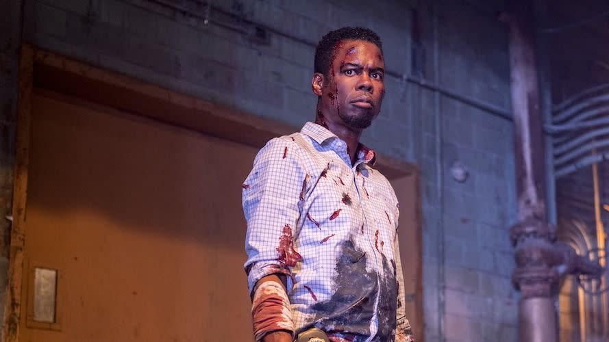 a man played by chris rock stands, bloodied, in a scene from spiral