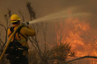 Jesse Vasquez, of the San Bernardino County Fire Department, hoses down hot spots from the Bobcat Fire on Saturday, Sept. 19, 2020, in Valyermo, Calif. (AP Photo/Marcio Jose Sanchez)