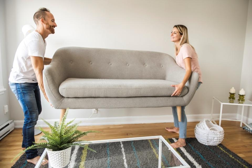 Couple moving a beige couch