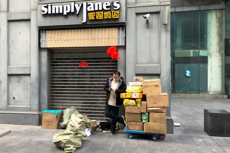 Man wearing a face mask checks his mobile phone next to a trolley of boxes on the streets of Huaqiangbei following an outbreak of the novel coronavirus in the country`