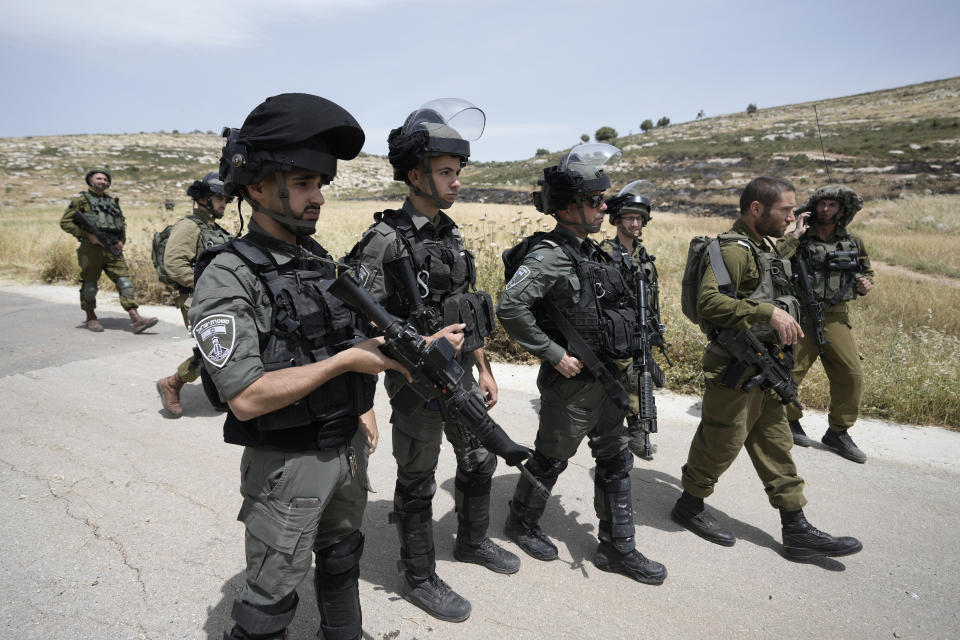 Israeli soldiers and Border Police are deployed at the site where Israeli settlers burned Palestinian cars and wheat fields in the village of al-Mughayyir near the West Bank city of Ramallah, Friday, May 26, 2023. Jewish settlers attacked Palestinian farmers and torched five vehicles in the village, the official Palestinian news agency reported. It added that five farmers were injured when settlers beat them. There was no immediate comment from the Israeli military.(AP Photo/Majdi Mohammed)