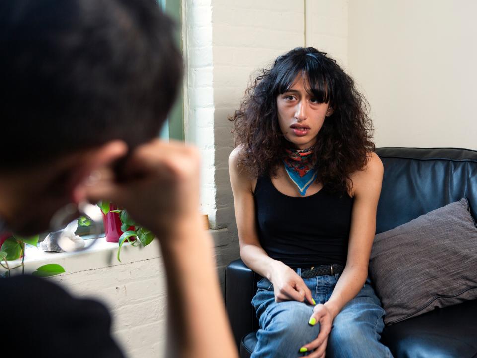A transgender woman sitting on a therapist's couch and crying