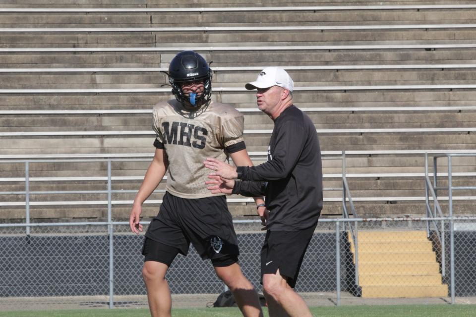 Milton football head coach Kelly Gillis (right) talks to rising senior Tate Williams during a spring practice on Wednesday, May 15, 2024.