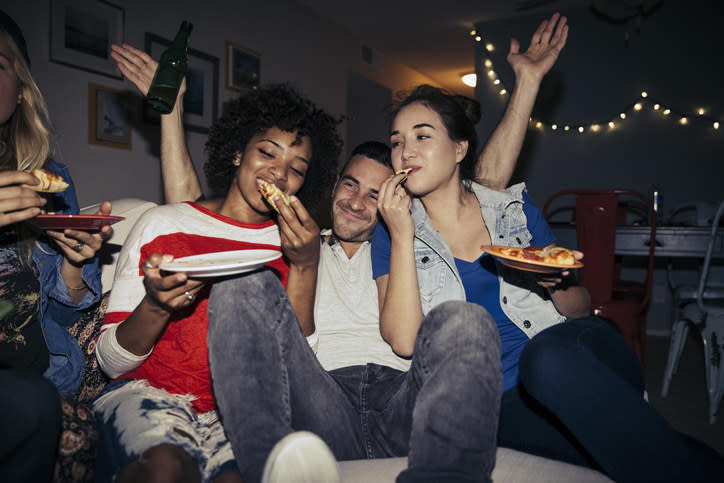 three people eating pizza in the living room