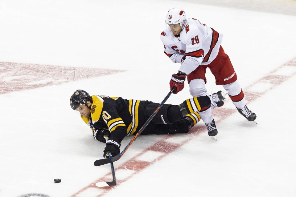 Boston Bruins' Anders Bjork (10) falls in front of Carolina Hurricanes' Sebastian Aho (20) during the third period of an NHL Eastern Conference Stanley Cup hockey playoff game in Toronto, Thursday, Aug. 13, 2020. (Chris Young/The Canadian Press via AP)