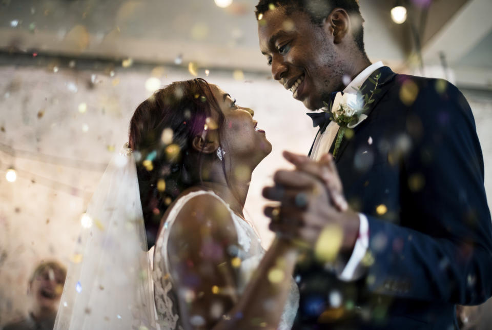 A bride and groom dance at their wedding as confetti falls around them