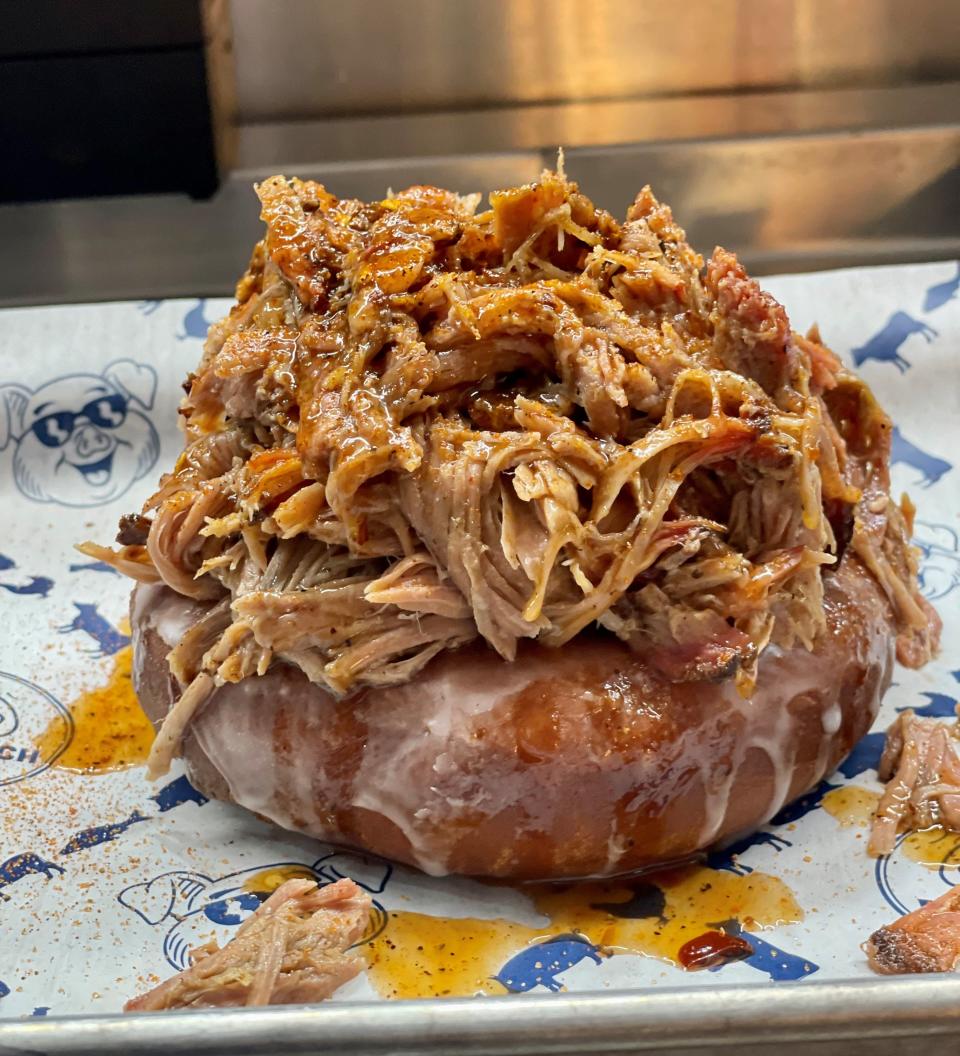 Meet the Porky Donut, a decadent dish offered as a special at Pig Beach BBQ's weekend brunch in West Palm Beach. A house-made glazed doughnut is crowned with pulled pork.