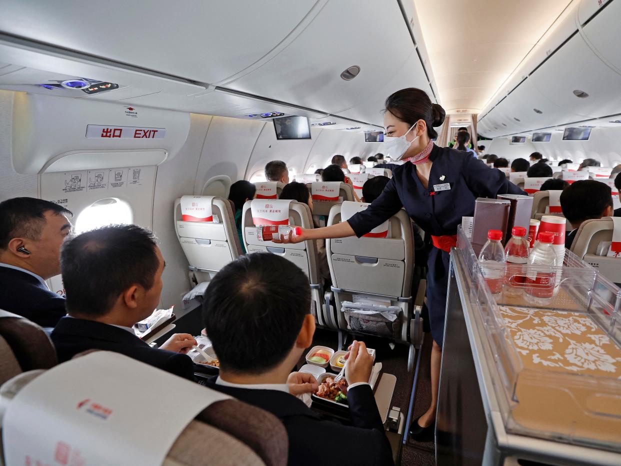 A flight attendant distributes bottles of water to passengers during the first commercial flight of China's first domestically produced passenger jet C919 from Shanghai to Beijing on May 28, 2023.