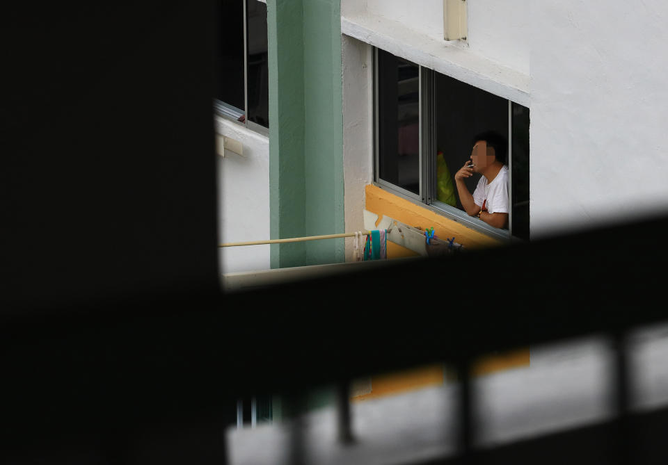 A man smokes at the window of his residential unit in Singapore. (PHOTO: Suhaimi Abdullah/Getty Images)