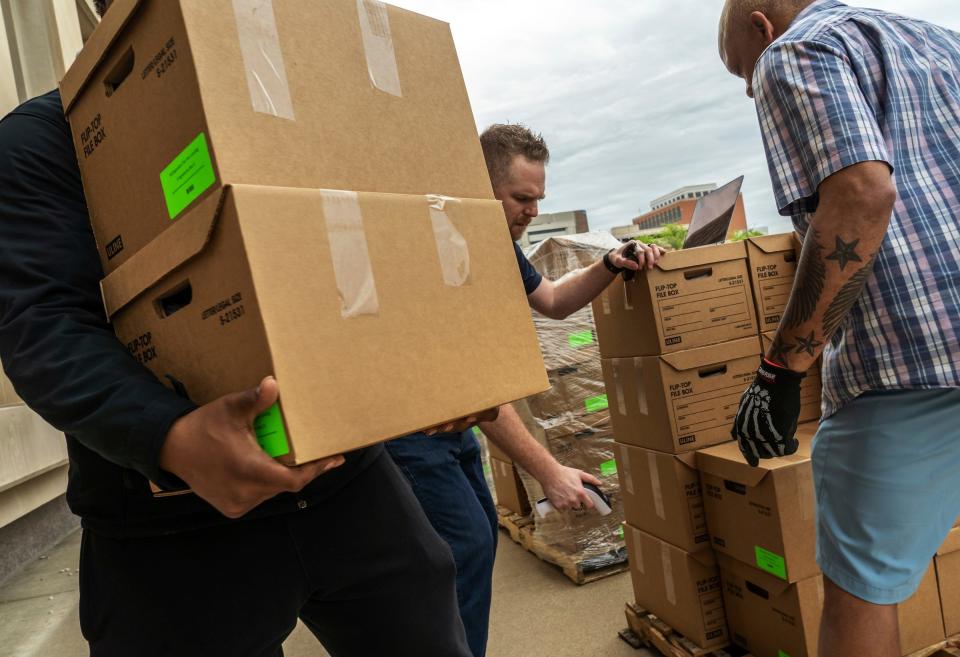 Some of the 135 boxes of signed petitions gathered for Michiganders for Fair Lending are scanned and hauled into the the Austin Building in downtown Lansing on Wednesday, June 1, 2022, as organizers of petition initiatives to change state laws turn in the signatures to introduce their proposals to the Legislature. 