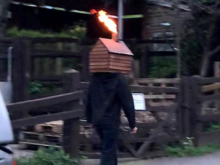 Man walks down street with disco shed on his head blasting fire from the chimney
