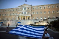 Anti-austerity demonstrators hold up a giant Greek national flag in front of the parliament in Athens, Greece July 22, 2015. REUTERS/Ronen Zvulun