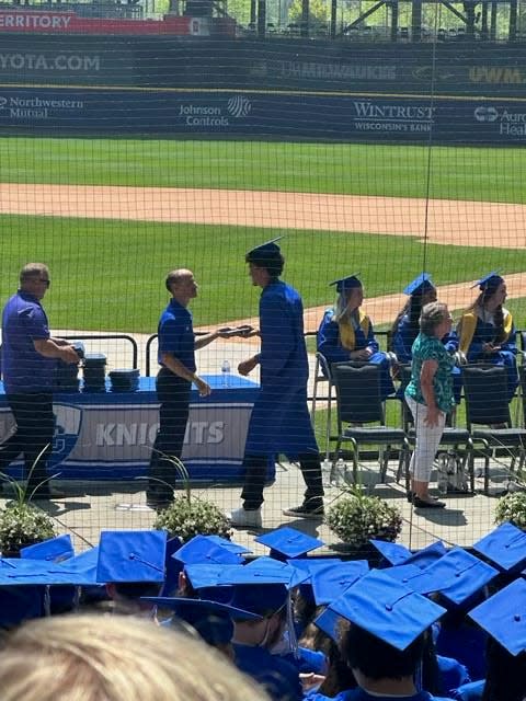 Izaac Neal receives his diploma case during Oak Creek High School's graduation ceremony at American Family Field June 24. Soon after, Neal would jump the rope and run the bases.