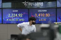 A currency trader stands near screens showing the Korea Composite Stock Price Index (KOSPI), left, and the foreign exchange rate between U.S. dollar and South Korean won at a foreign exchange dealing room in Seoul, South Korea, Friday, Oct. 7, 2022. Asian shares followed Wall Street lower Friday ahead of U.S. jobs data investors hope will persuade the Federal Reserve to ease off plans for more interest rate hikes. (AP Photo/Lee Jin-man)