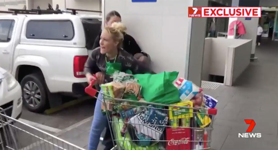 A woman pushing a trolley and yelling at witnesses.