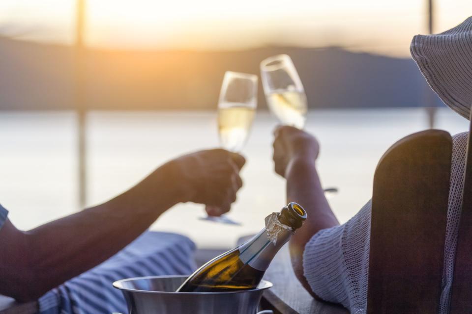 couple relaxing and drinking champagne on deck chairs on the waterfront