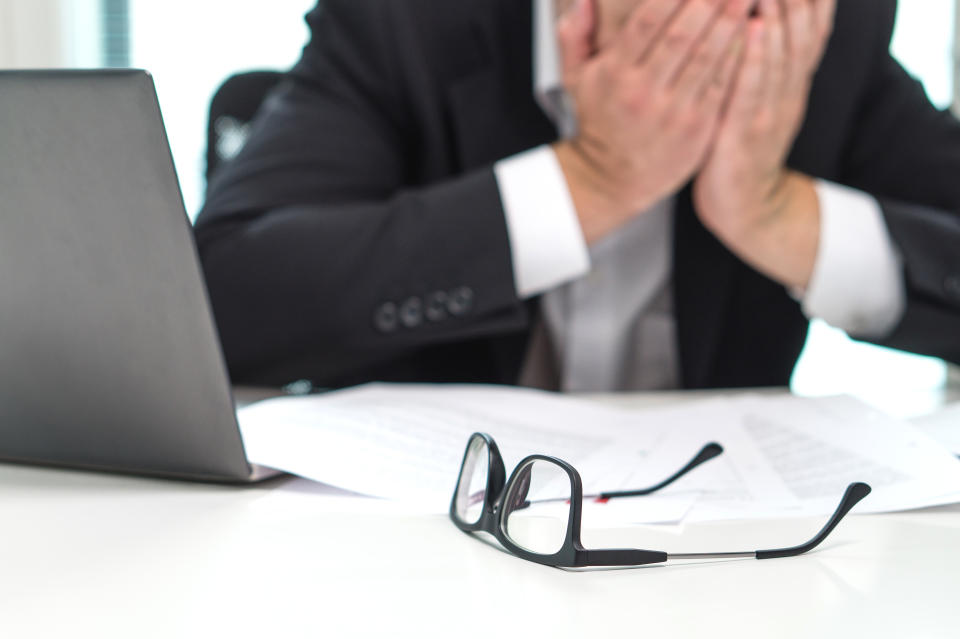 Stressed business man covering face with hands in office. Working over time or too much. Problem with failing business or confusion with crisis. Entrepreneur in bankruptcy.