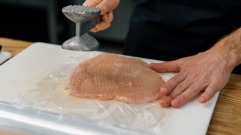 person flattening a chicken breast