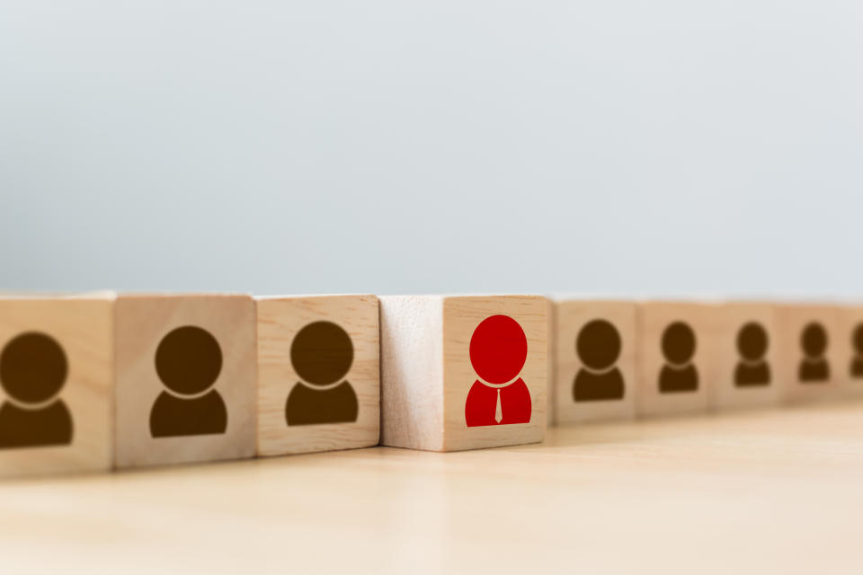 Building blocks stamped with brown human figures and a single red figure to represent a hiring process.