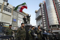 An anti-riot police officer waves a representation of the Iranian flag during a street celebration after Iran's national soccer team defeated Wales in Qatar's World Cup, at Sadeghieh Sq. in Tehran, Iran, Friday, Nov. 25, 2022. Iran's political turmoil has cast a shadow over Iran's matches at the World Cup, spurring tension between those who back the team and those who accuse players of not doing enough to support the protests that started Sept. 16 over the death of a 22-year-old woman in the custody of the morality police. (AP Photo/Vahid Salemi)