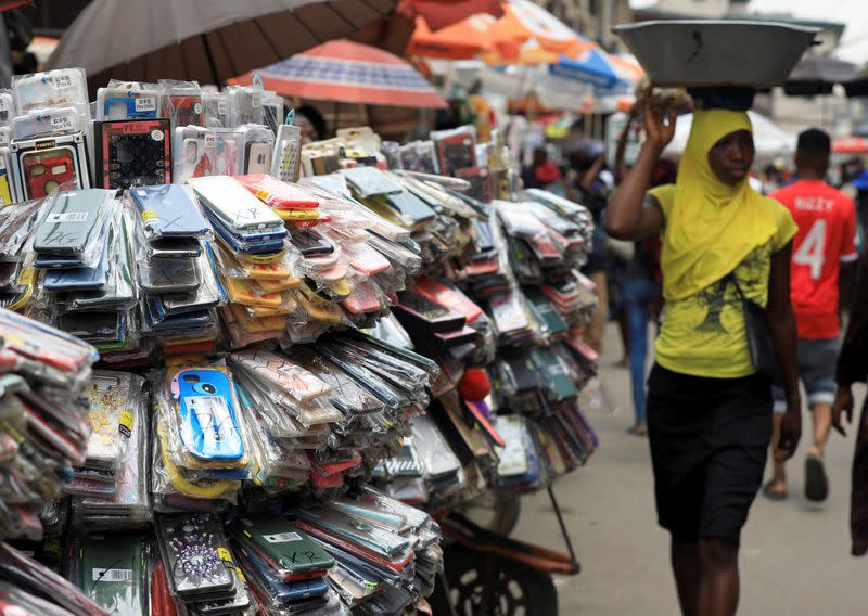 A woman walks past phone accessories arranged on a wheelbarrow in Balogun market in Nigeria's commercial capital, Lagos