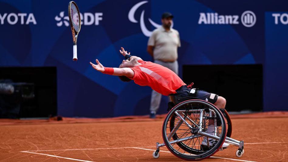 Alfie Hewett leans back in his wheelchair and throws his racquet in the air in celebration after winning the Paralympic wheelchair tennis men's doubles gold medal with Gordon Reid