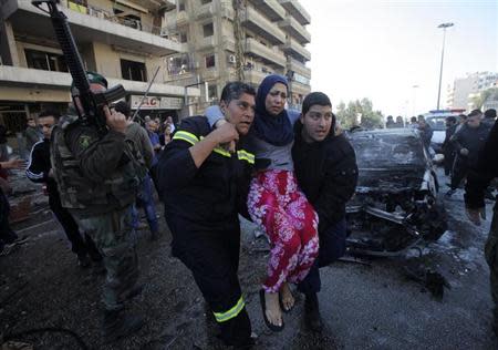 Civil defence members carry a wounded woman as a Lebanese Army soldier secures the area at the site of an explosion in the southern suburbs of Beirut February 19, 2014. REUTERS/Mahmoud Kheir